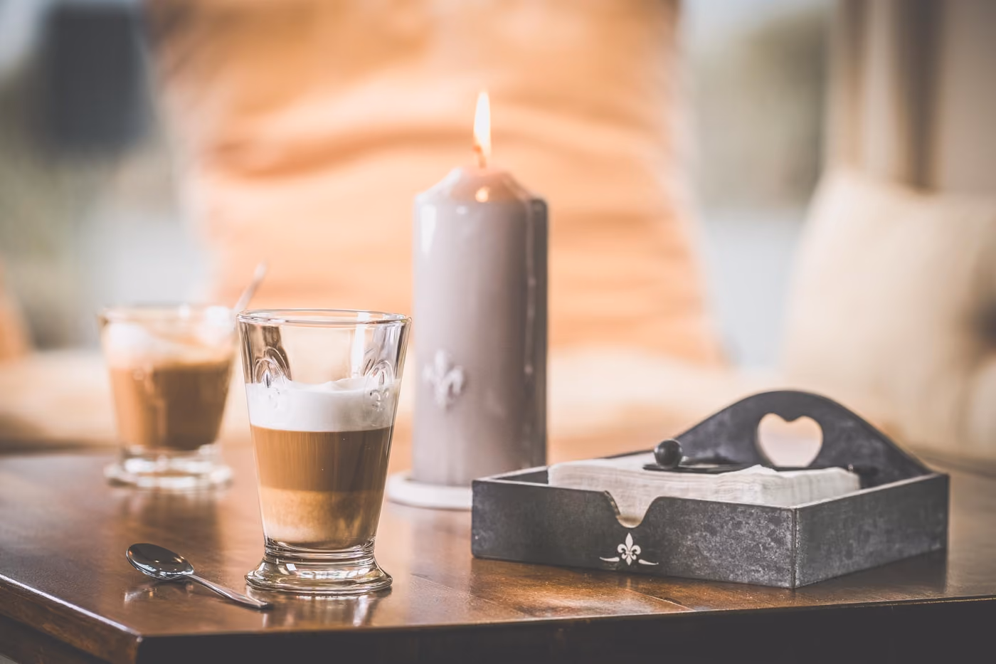 Zwei Latte-macchiato-Gläser mit Milchschaumschichten auf einem Holztisch im Gastraum