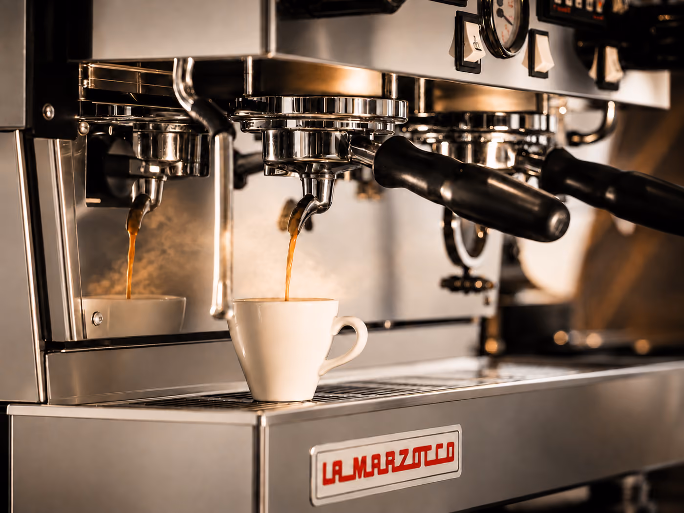 Espresso läuft aus dem Siebträger der La-Marzocco-Maschine in eine weiße Tasse